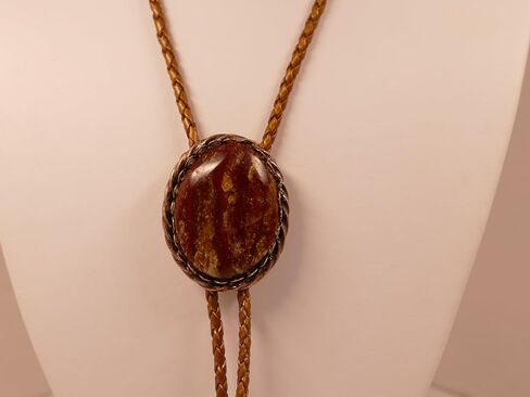 A Deep Red and Gold Jasper Cabochon is in a Copper Tone Bolo Slide with Copprt Tone Leather Cord and Swirl Tips in Saudi Arabia