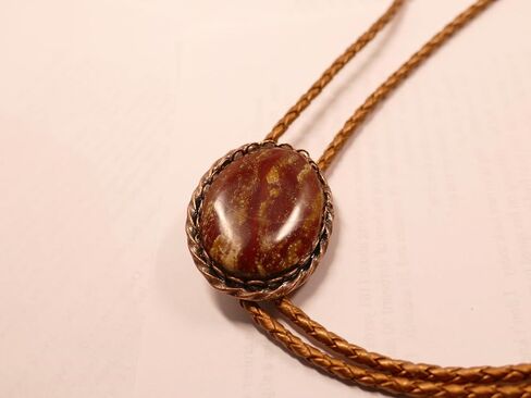 A Deep Red and Gold Jasper Cabochon is in a Copper Tone Bolo Slide with Copprt Tone Leather Cord and Swirl Tips in Saudi Arabia