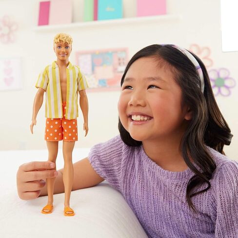 دمية كين من Barbie Fashionistas Style #252 ذات شعر أشقر، ترتدي شورتًا منقطًا باللونين البرتقالي والأصفر مع قميص مخطط باللونين الأصفر والأبيض، وحذاء برتقالي in Kuwait